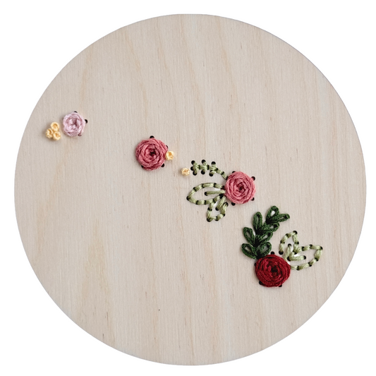 Embroidered floral designs on a wooden hoop with a white background