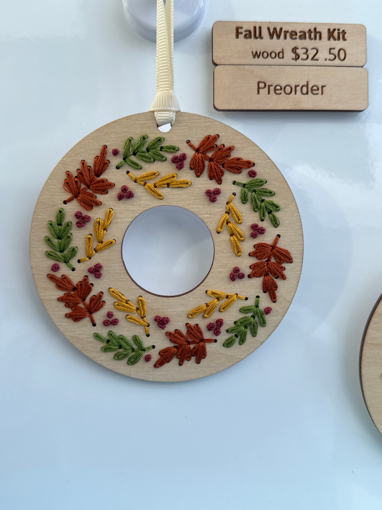 Wooden wreath kit with embroidered leaves on a white background