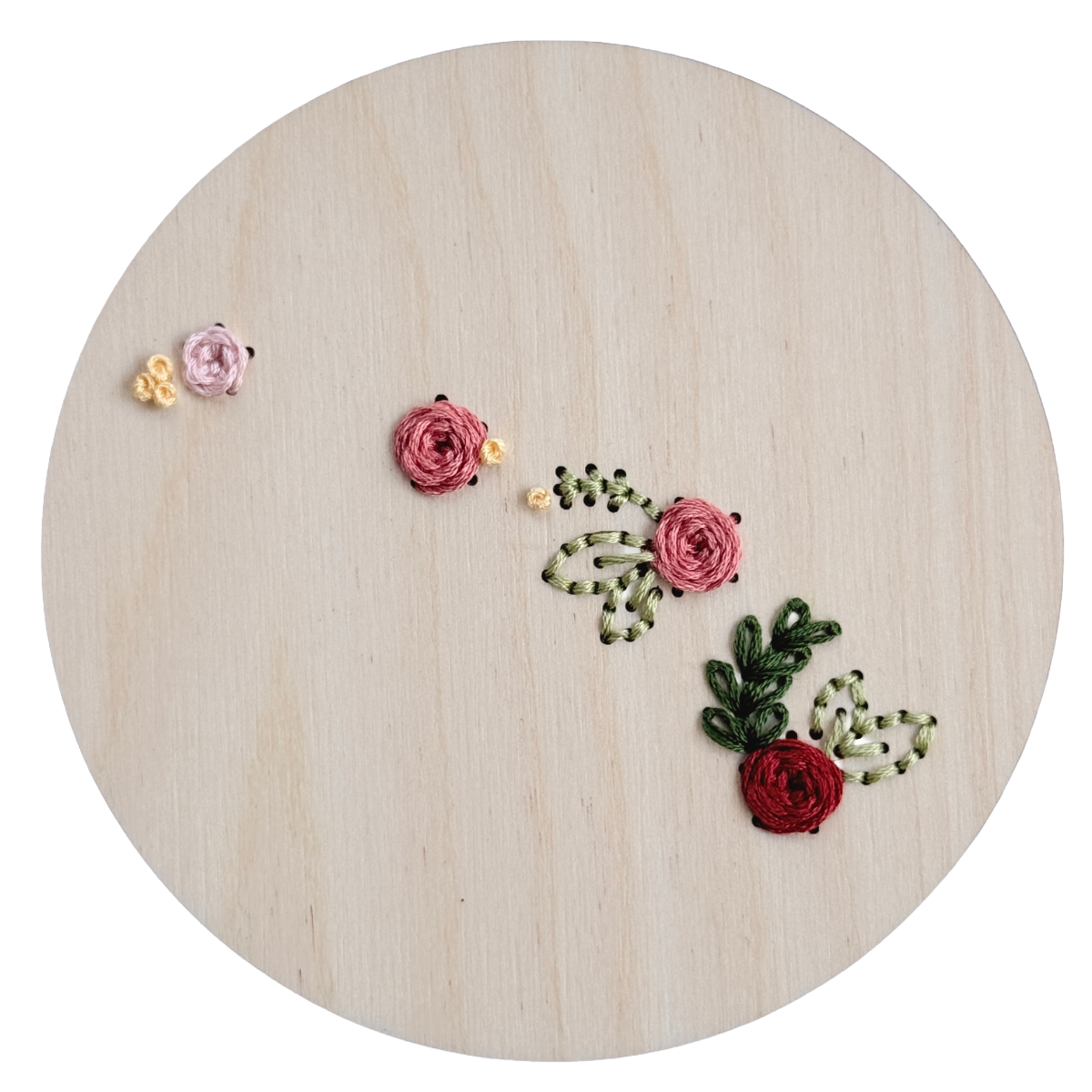 Embroidered floral designs on a wooden hoop with a white background